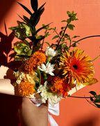 Bouquet of flowers with orange, yellow, and white colors against a warm-toned background