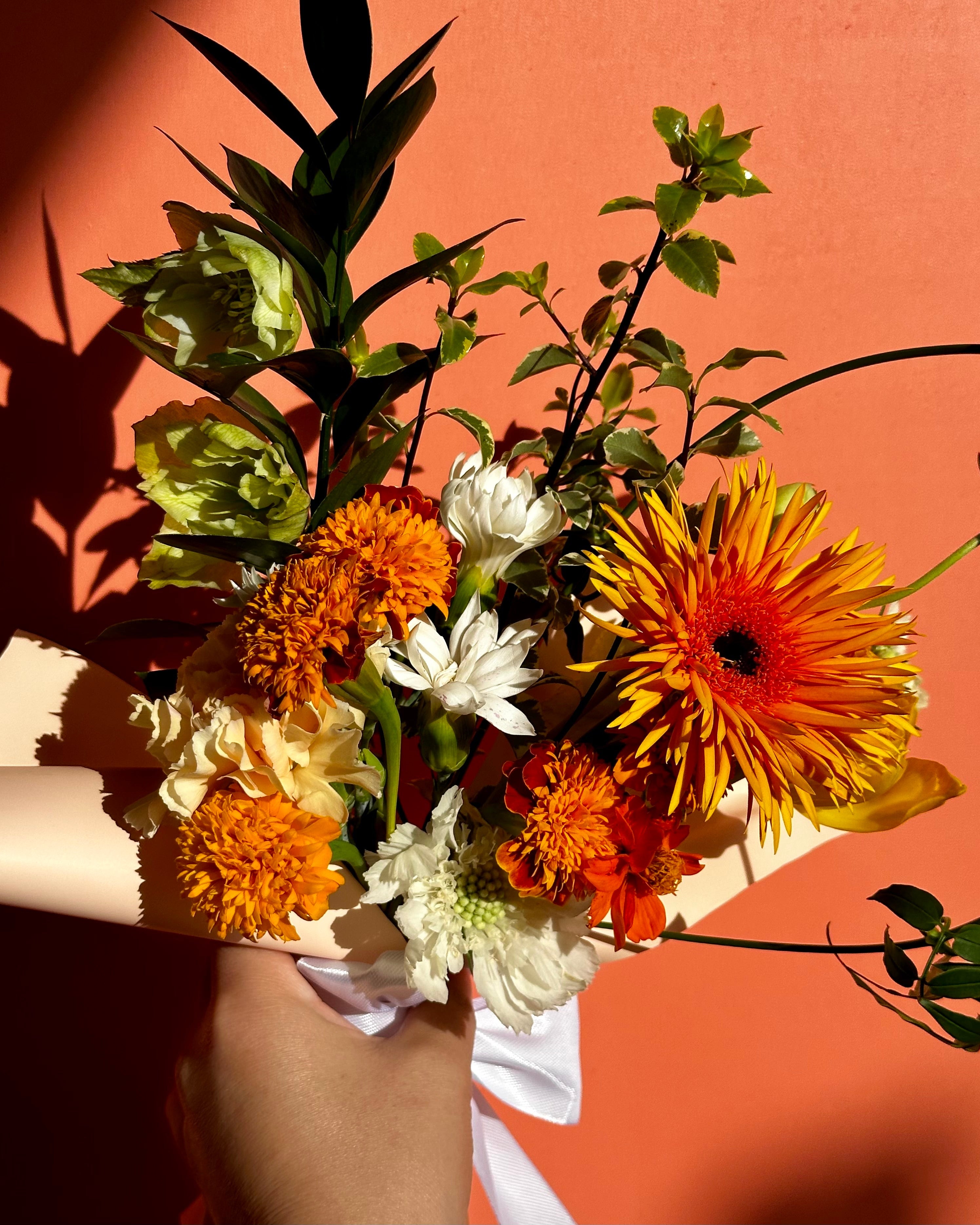 Bouquet of flowers with orange, yellow, and white colors against a warm-toned background